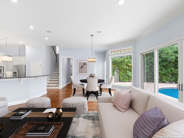 living room featuring crown molding, sink, light wood-type flooring, and an inviting chandelier