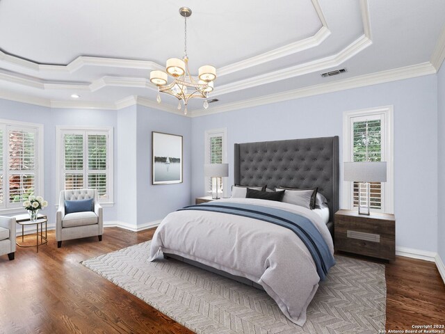 bedroom with an inviting chandelier, ornamental molding, dark hardwood / wood-style floors, and a tray ceiling