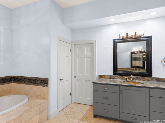 bathroom with tiled bath, vanity, and tile flooring