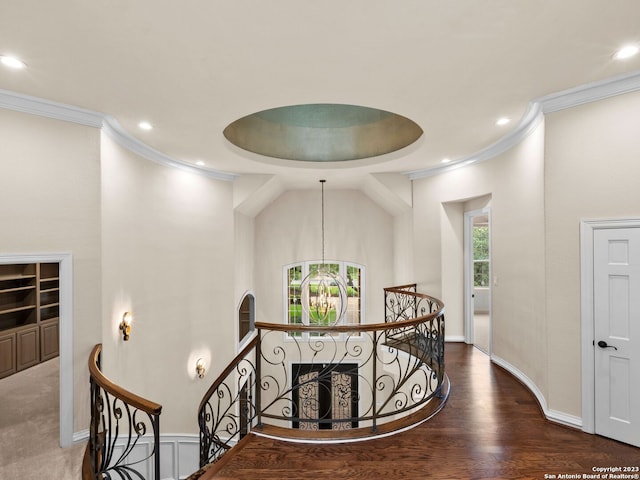 stairs featuring a raised ceiling, an inviting chandelier, a healthy amount of sunlight, and dark colored carpet