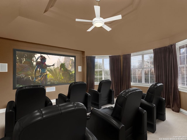 carpeted home theater with ceiling fan and a raised ceiling