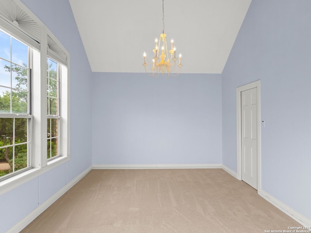 carpeted empty room featuring a chandelier and vaulted ceiling