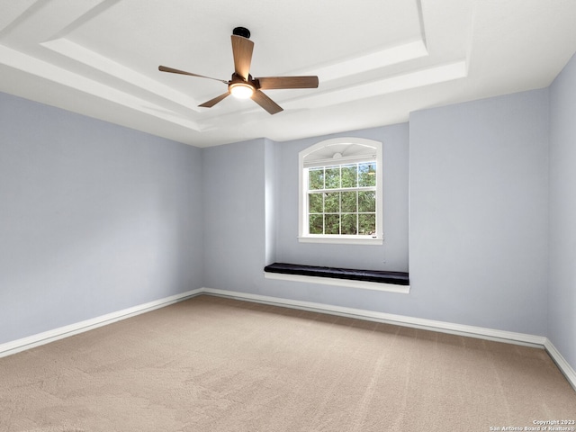 carpeted spare room featuring a tray ceiling and ceiling fan