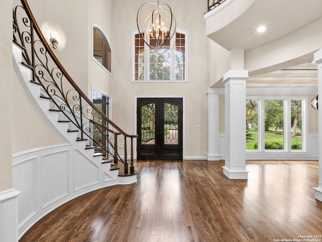 foyer featuring dark hardwood / wood-style flooring, a notable chandelier, decorative columns, and french doors