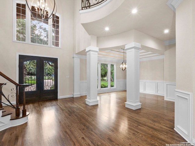 entrance foyer with french doors, an inviting chandelier, dark hardwood / wood-style floors, and ornate columns