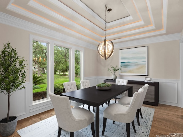 dining space featuring a raised ceiling, an inviting chandelier, light hardwood / wood-style floors, and ornamental molding