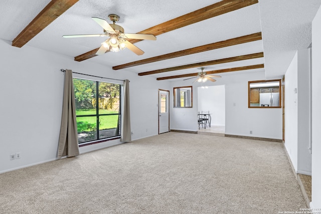 unfurnished living room featuring beamed ceiling, ceiling fan, a textured ceiling, and carpet