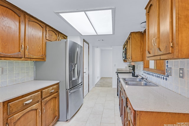 kitchen with tasteful backsplash, range with electric cooktop, stainless steel refrigerator with ice dispenser, light tile floors, and sink