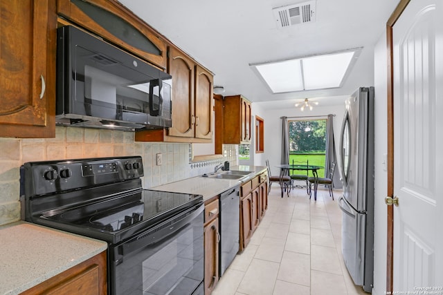 kitchen featuring a chandelier, tasteful backsplash, black appliances, sink, and light tile floors