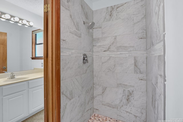 bathroom with a tile shower and vanity with extensive cabinet space