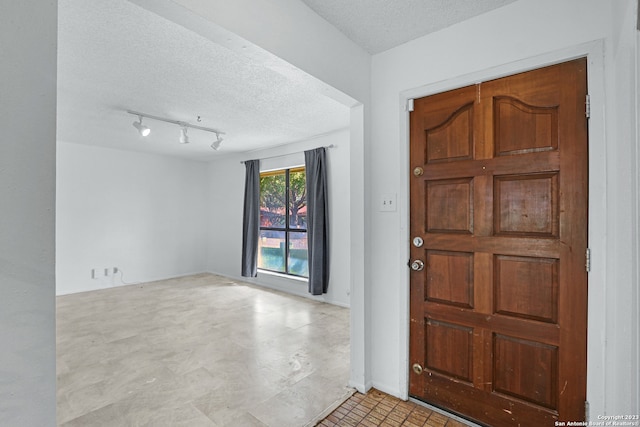 entrance foyer featuring a textured ceiling, light tile floors, and rail lighting