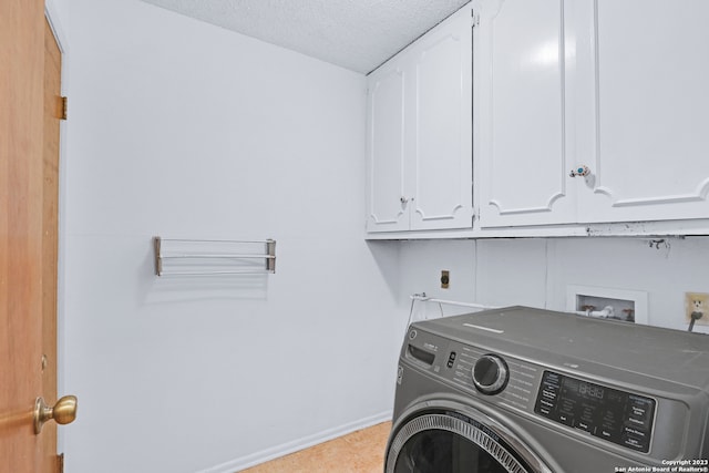 washroom with cabinets, a textured ceiling, washer / dryer, and light tile floors