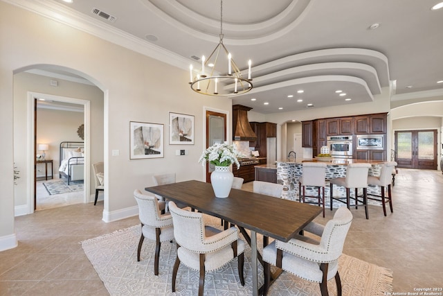 dining area featuring an inviting chandelier, a raised ceiling, light tile floors, crown molding, and french doors