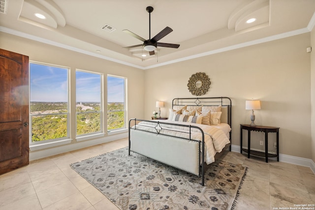 tiled bedroom featuring a tray ceiling, ornamental molding, and ceiling fan