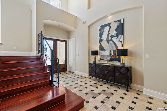 foyer with a towering ceiling, light tile flooring, and a wealth of natural light