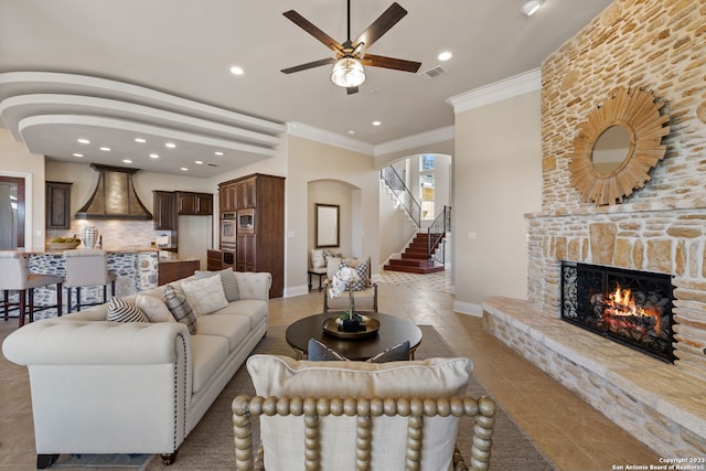 tiled living room with ceiling fan, ornamental molding, and a fireplace