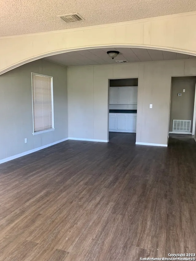 unfurnished room with a textured ceiling and dark wood-type flooring