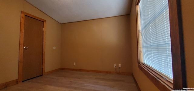 spare room with light hardwood / wood-style flooring and vaulted ceiling