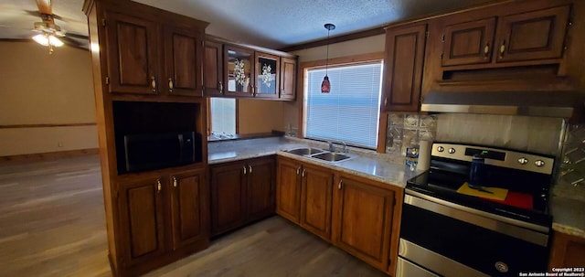 kitchen featuring decorative light fixtures, ceiling fan, light hardwood / wood-style flooring, stainless steel range with electric stovetop, and sink