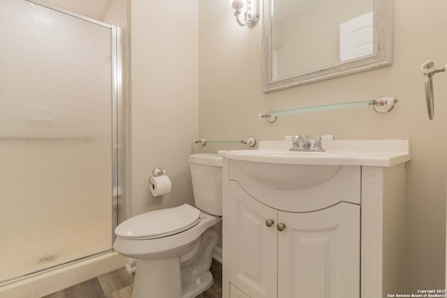 bathroom featuring toilet, hardwood / wood-style floors, walk in shower, and vanity