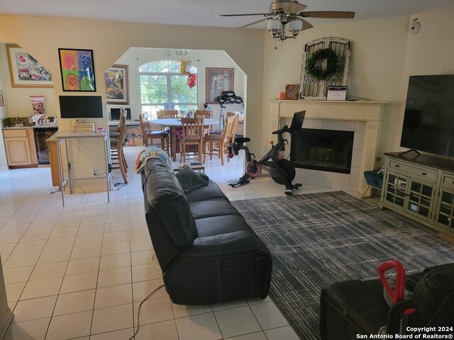 tiled living room with wine cooler, ceiling fan, and a tiled fireplace