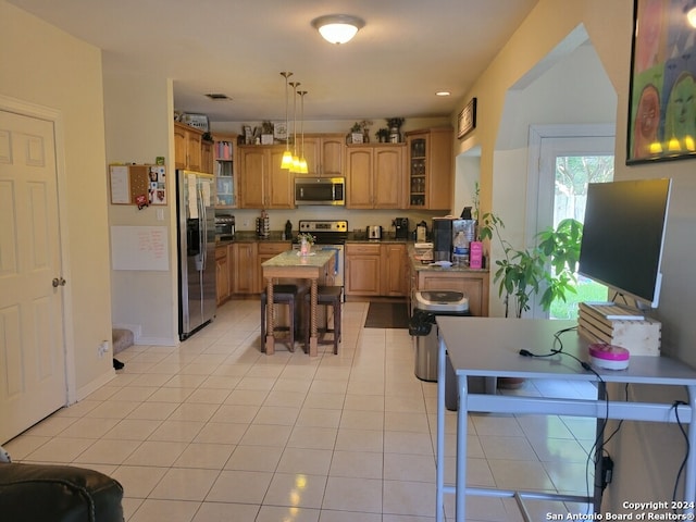 kitchen featuring decorative light fixtures, light tile patterned floors, a breakfast bar area, and appliances with stainless steel finishes