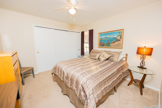 bedroom with light colored carpet, ceiling fan, and a closet