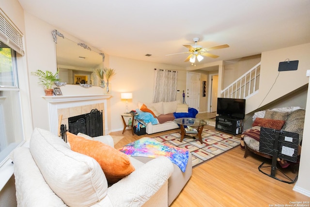 living room featuring ceiling fan, hardwood / wood-style floors, and a fireplace