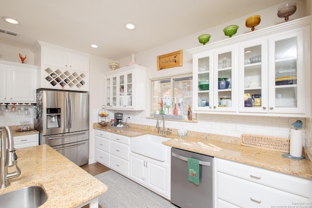 kitchen featuring light stone countertops, white cabinetry, sink, and appliances with stainless steel finishes