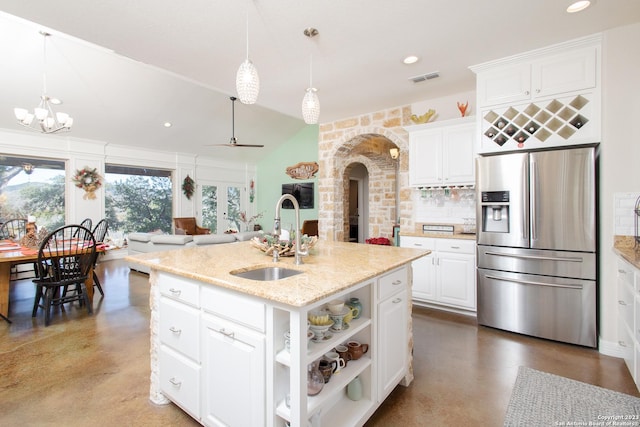 kitchen featuring sink, hanging light fixtures, stainless steel fridge with ice dispenser, an island with sink, and white cabinets