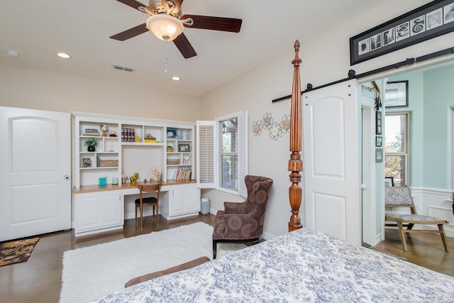 bedroom with multiple windows, a barn door, ceiling fan, and built in desk