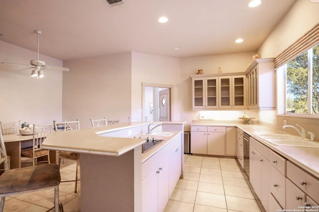 kitchen featuring a kitchen breakfast bar, sink, ceiling fan, light tile patterned floors, and an island with sink