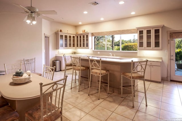 interior space featuring a kitchen breakfast bar, a kitchen island, light tile patterned flooring, and ceiling fan