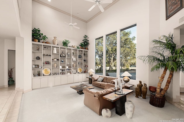 living room with ceiling fan, a high ceiling, and ornamental molding