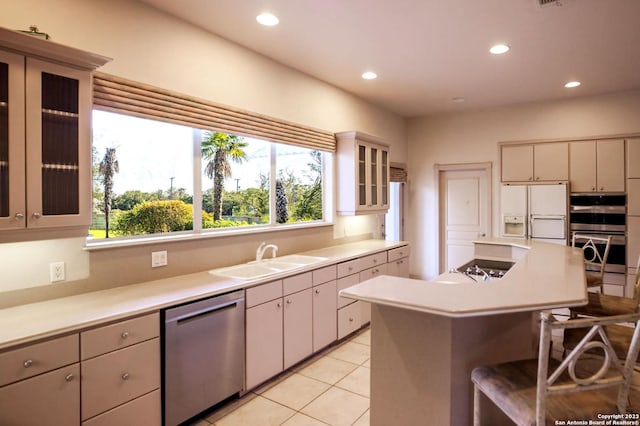 kitchen with sink, a center island, a breakfast bar, light tile patterned floors, and appliances with stainless steel finishes