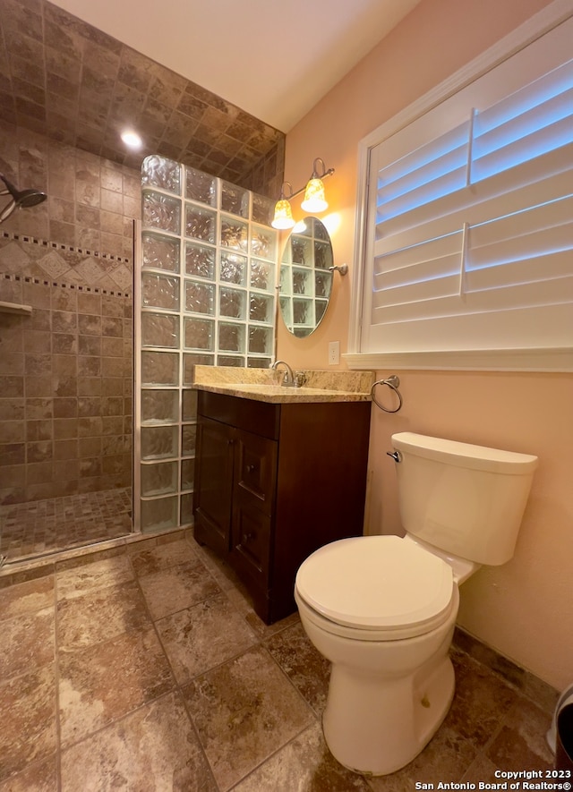 bathroom featuring tiled shower, vanity, tile patterned flooring, and toilet