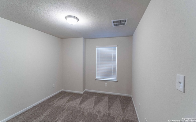 carpeted empty room with a textured ceiling