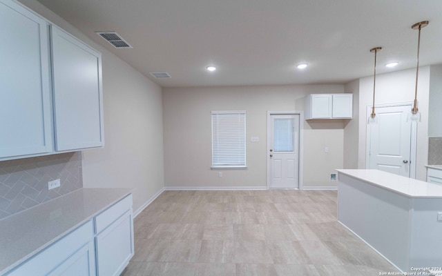 kitchen with hanging light fixtures, white cabinetry, light tile patterned floors, and tasteful backsplash