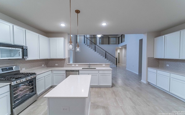 kitchen with stainless steel appliances, sink, backsplash, decorative light fixtures, and a center island