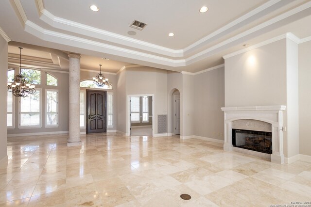 unfurnished living room featuring a high end fireplace, a raised ceiling, an inviting chandelier, and ornate columns