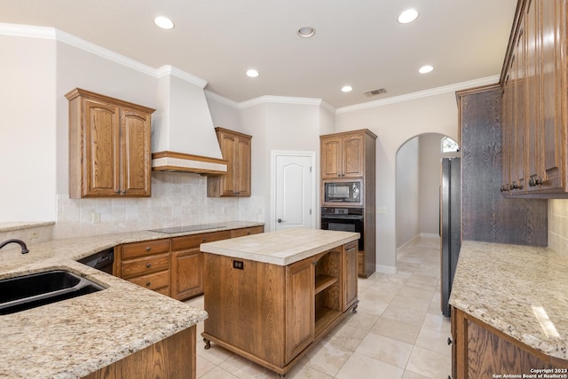 kitchen with visible vents, arched walkways, custom exhaust hood, black appliances, and a sink