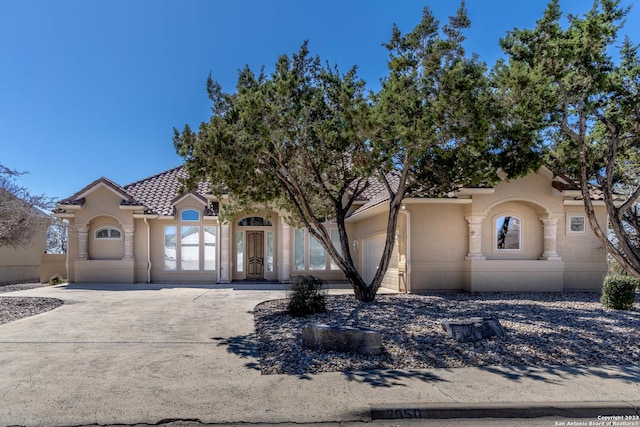 view of front facade featuring a garage, driveway, a tiled roof, and stucco siding