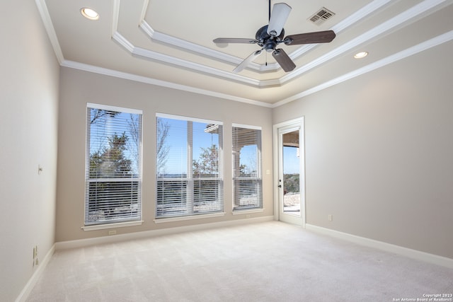 carpeted spare room with ceiling fan, a tray ceiling, a wealth of natural light, and ornamental molding