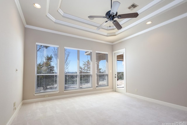 unfurnished room featuring light colored carpet, visible vents, baseboards, ornamental molding, and a raised ceiling