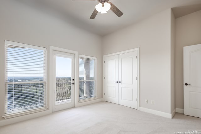 unfurnished bedroom featuring access to exterior, multiple windows, and light colored carpet