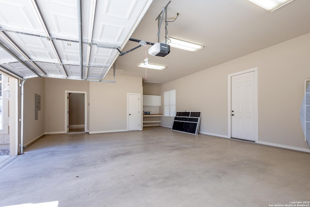 garage featuring baseboards, electric panel, and a garage door opener