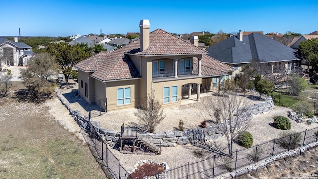 rear view of property featuring a tile roof, fence, and stucco siding