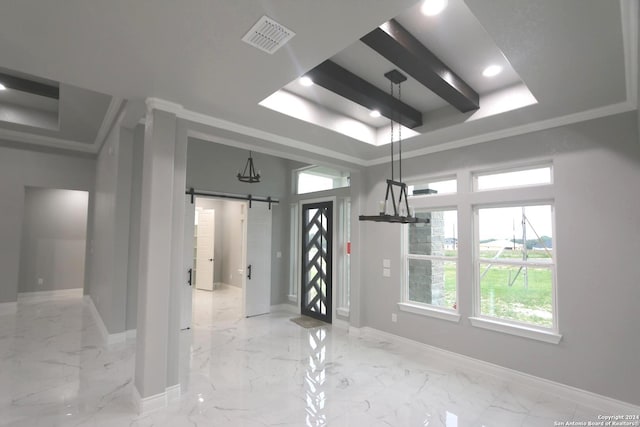 interior space with ornamental molding, a raised ceiling, and a barn door