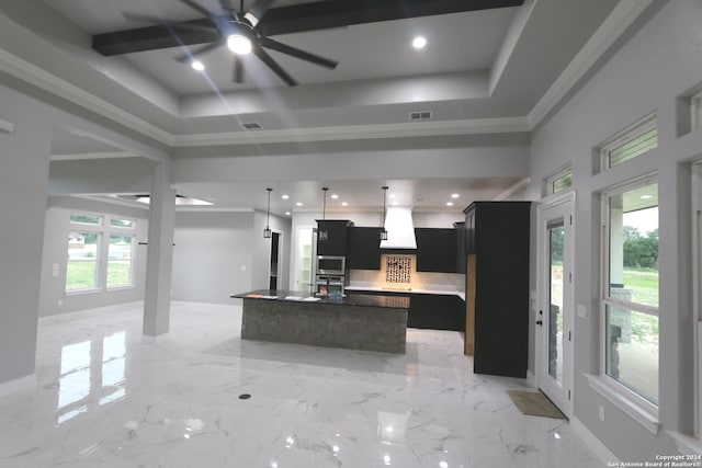 kitchen featuring a tray ceiling, a center island with sink, and a wealth of natural light