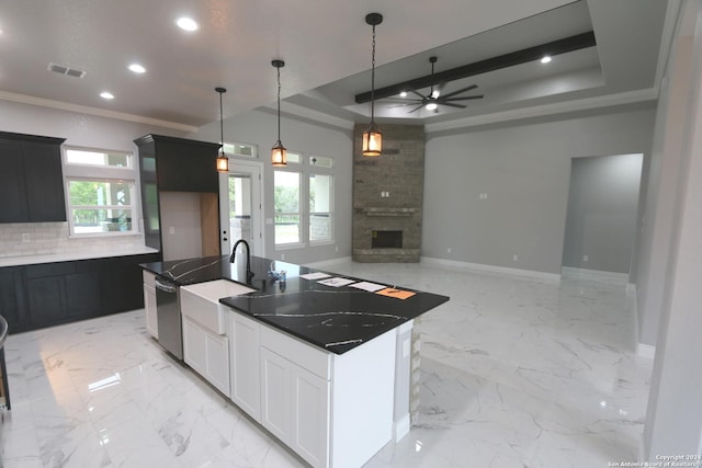 kitchen with white cabinetry, a tray ceiling, a fireplace, and ornamental molding